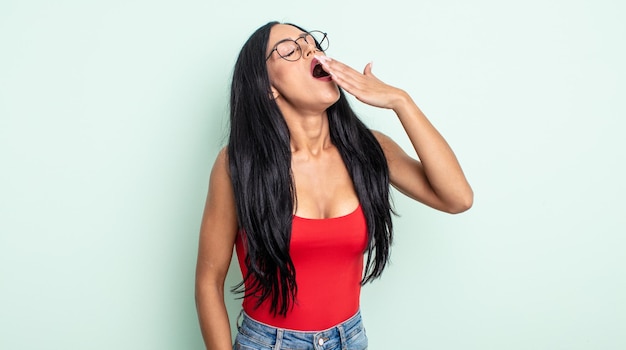 Pretty hispanic woman yawning lazily early in the morning, waking and looking sleepy, tired and bored