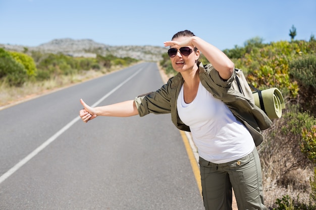 Foto pretty autostoppista che sporge il pollice sulla strada