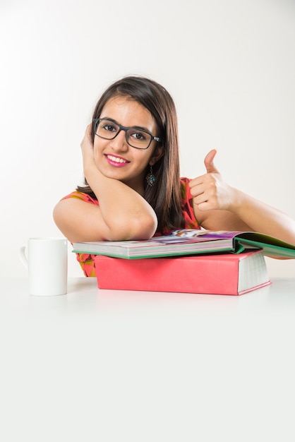 Bella ragazza indiana asiatica collage che studia su tablet con una pila di libri