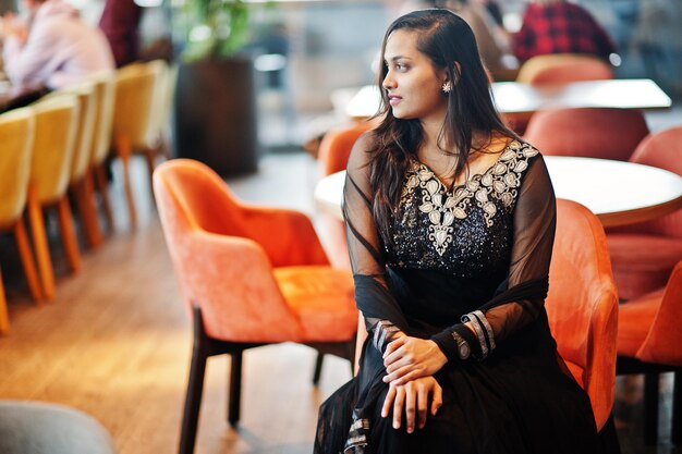 Pretty indian girl in black saree dress posed at restaurant