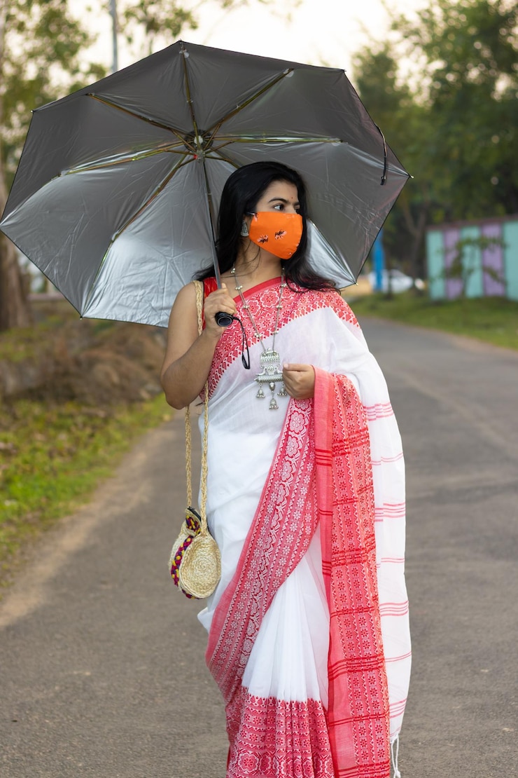 फोटो a pretty indian woman in red saree and long hair wearing protective cotton nose mask walking