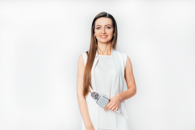 Pretty journalist in a white suit stands with a microphone in her hand 