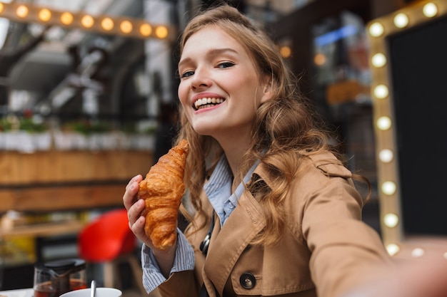 Pretty joyful girl in trench coat happily 