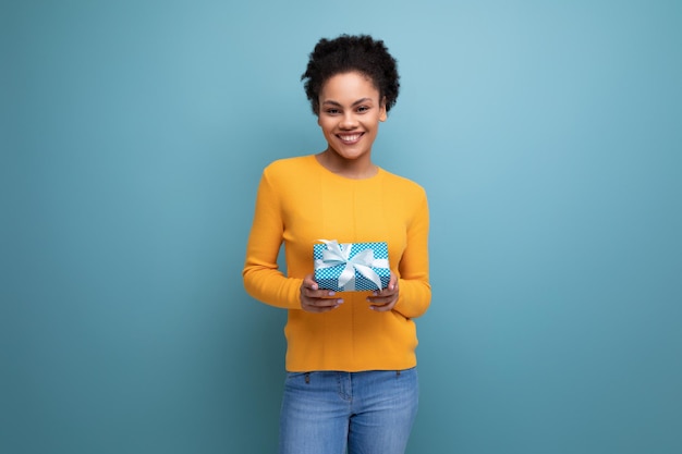 Pretty joyful s latin woman with afro hair in casual yellow sweater got a birthday gift