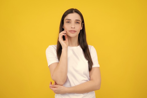 Pretty joyfully female model looking with satisfaction studio portrait of looking beautiful woman isolated against yellow background