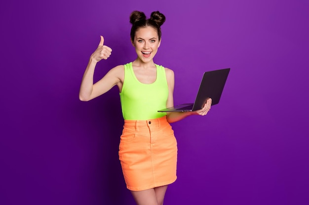 Pretty lady hold notebook raise thumb up approve excellent network wear green singlet jeans skirt isolated violet color background