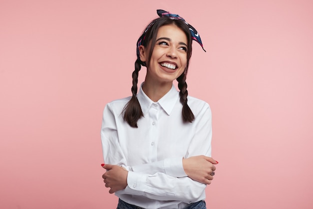 Bella signora con le braccia incrociate sorridente sul rosa