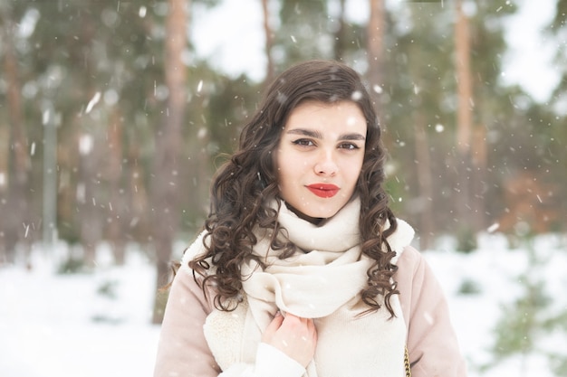 雪の降る天気で森の中を歩く長い髪のきれいな女性