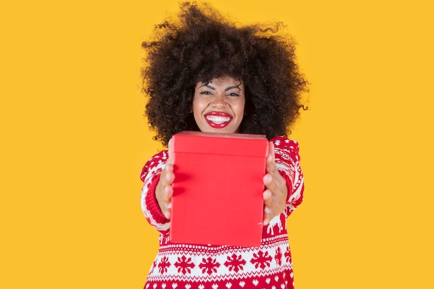 Pretty latin hispanic woman, christmas with a gift in hand, yellow background