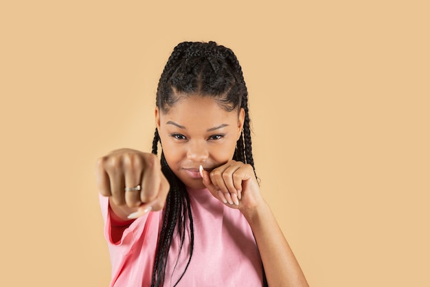 Pretty latin woman makes fist gesture on yellow background