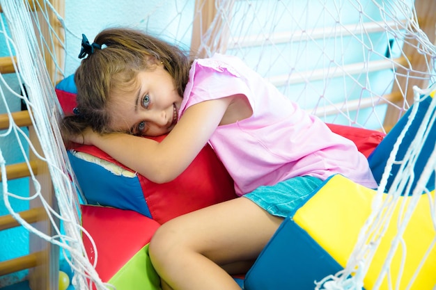 Pretty, light-eyed girl lying on mats in her school gymnasium.