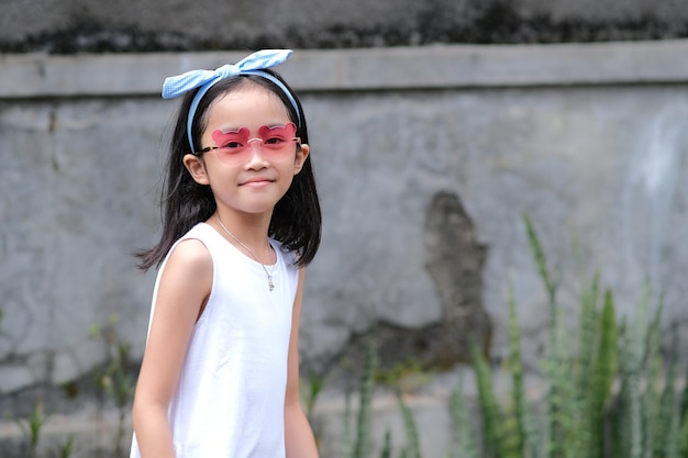 Pretty little Asian girl standing alone wearing toy glasses