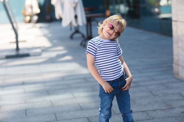 Pretty little boy on a skate board. Emotional kid outdoors. Cute child skating wearing sunglasses.