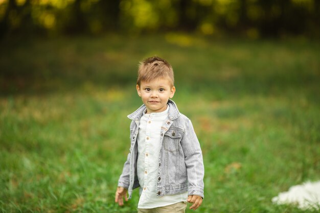 Pretty little caucasian boy in stylish clothes goes for a walk