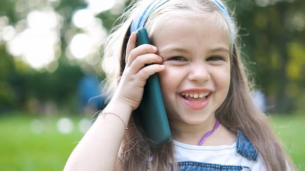 Pretty little child girl having conversation on her mobile phone in summer park