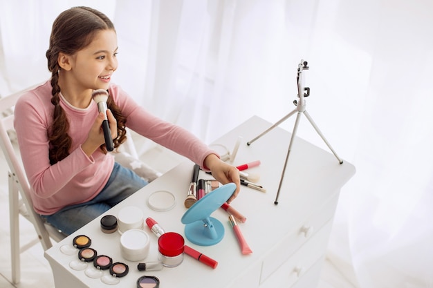 Pretty little girl acting like a makeup artist in front of the camera