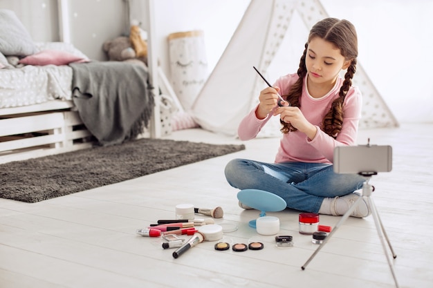 Pretty little girl acting like a makeup artist in front of the camera