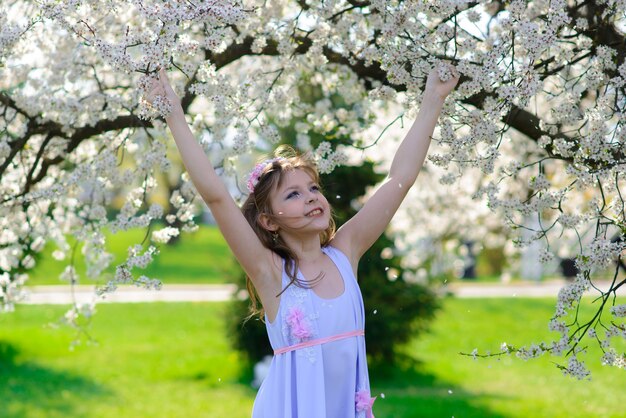 Pretty little girl in blooming apple tree garden on beautiful spring day