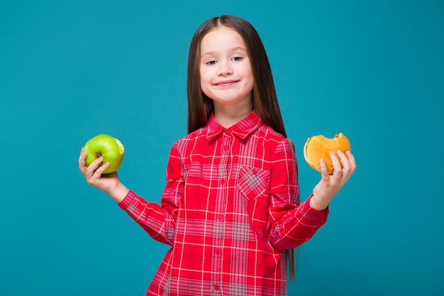 Pretty, little girl in checkered shirt with brunet hair hold burger