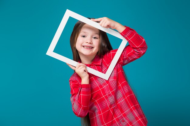 Pretty, little girl in checkered shirt with brunet hair hold picture frame