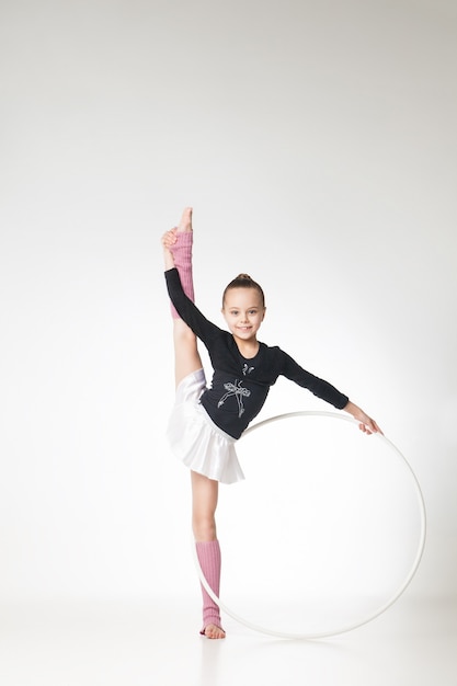 Pretty little girl doing gymnastics over white background