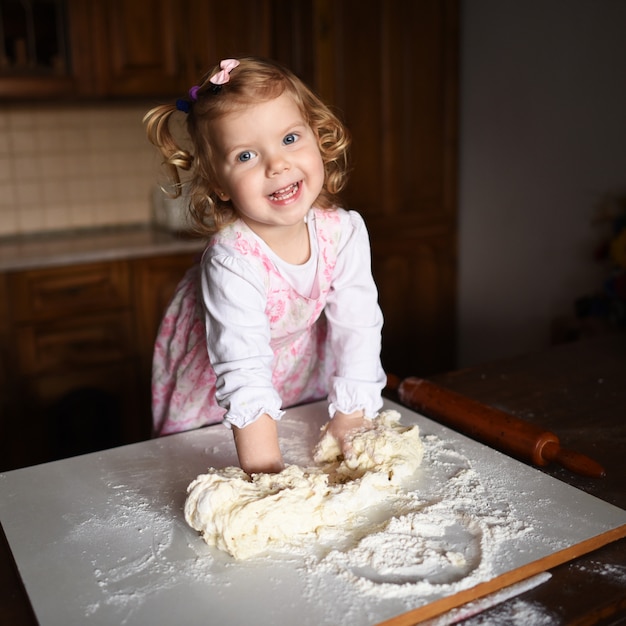 Pretty little girl having fun kneads dough