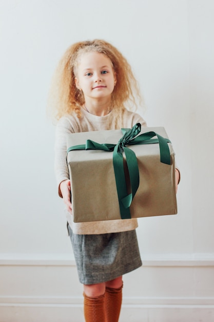 Pretty little girl holding big gift box