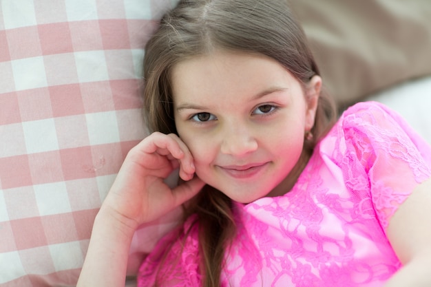 Фото Хорошенькая девочка в розовом платье принцессы в постели с подушкой