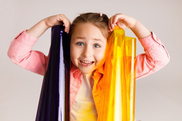 Photo pretty little girl learning colors and their combinations using colored foil, early development and learning concept