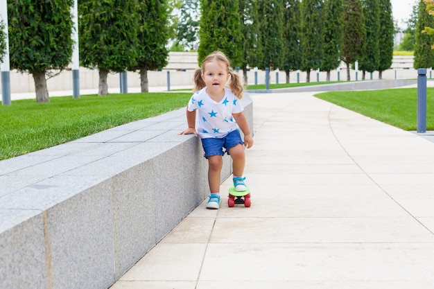 Pretty little girl learning to skate to skateboard