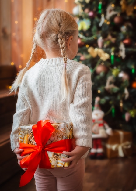 Довольно маленькая девочка открывает рождественский подарок.