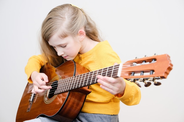 Foto bambina graziosa che suona la chitarra acustica