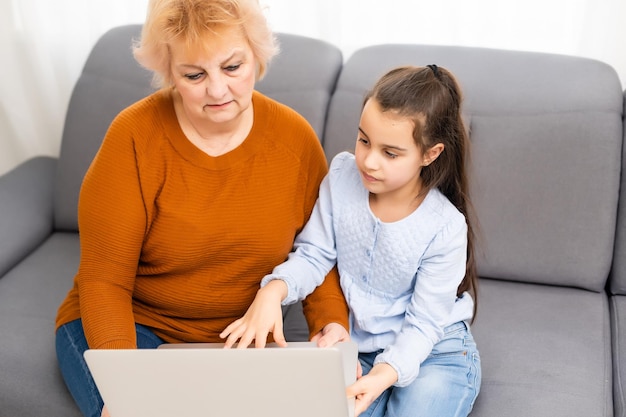 pretty little girl playing her grandmother's laptop at home.