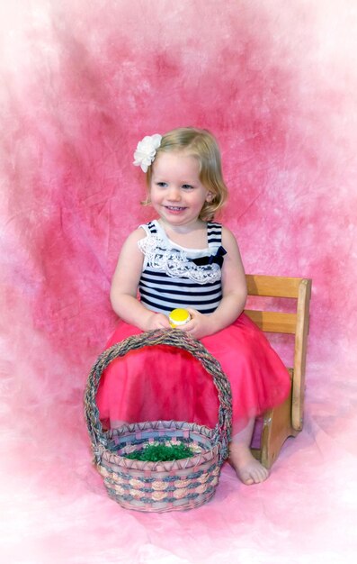 Pretty little girl poses with an easter basket and easter eggs person barefoot