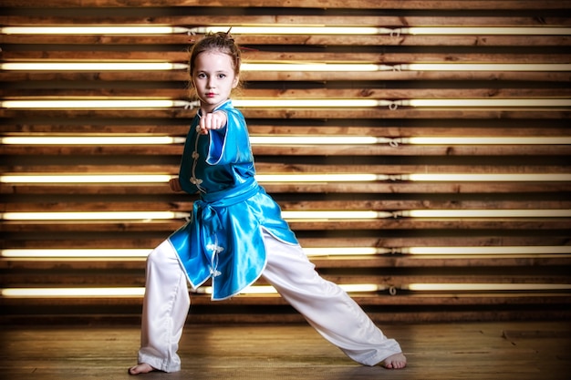 Pretty little girl in the room in sportswear for martial arts is Wushu or kung fu