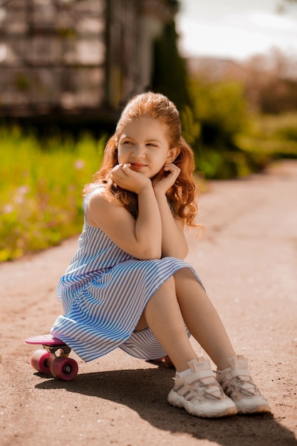 Красивая маленькая девочка сидит на скейтборде