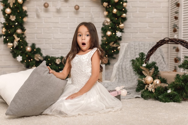 Bambina graziosa in un vestito bianco a natale