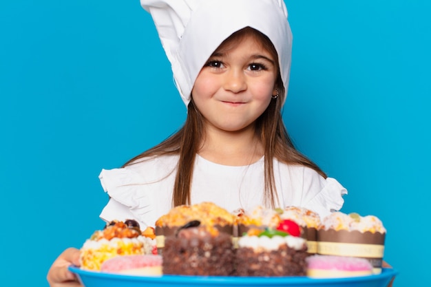 Bambina graziosa con torte e dolci