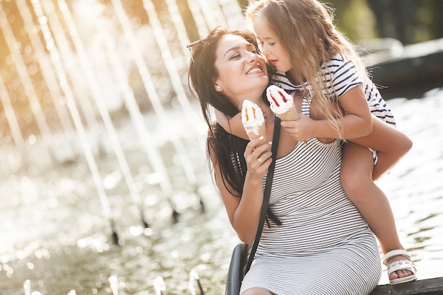 Pretty little girl with her mother eating ice cream