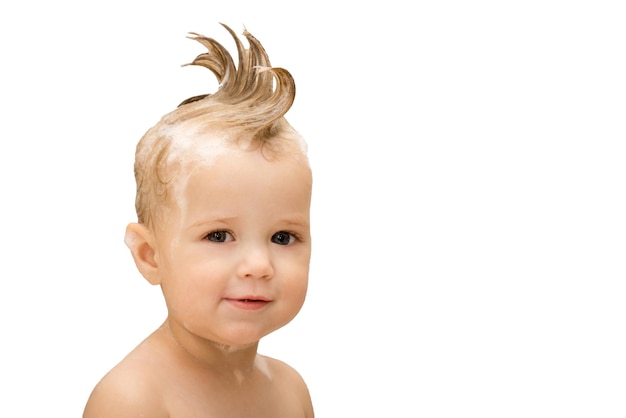 Красивая маленькая девочка с ирокезом и мыльной пеной на волосах на сером изолированном фоне