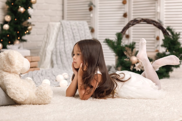 Pretty little girl with a teddy bear on Christmas