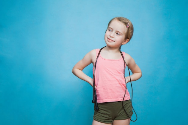 Pretty little sporty girl with skipping rope on blue