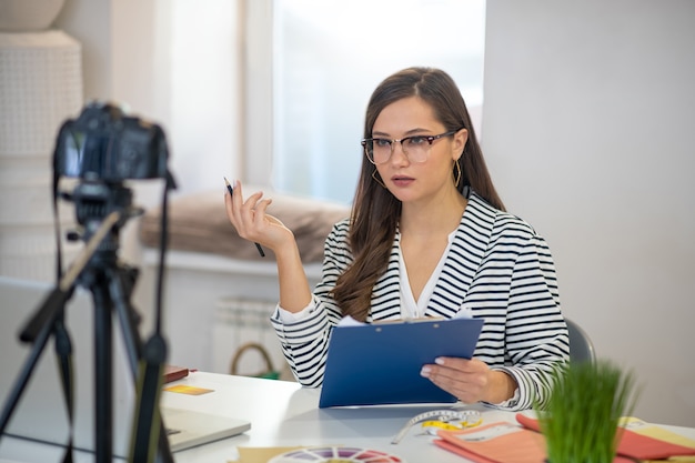 Pretty long haired woman sitting in front of the camera while having a video tutorial