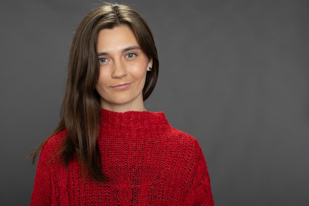 Pretty longhaired brunette girl posing in red sweater looking at front