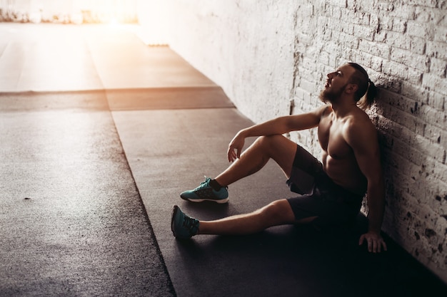 Uomo grazioso stanco dopo il sollevamento pesi in palestra