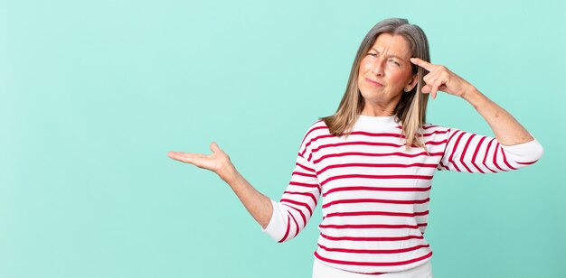 Pretty middle age woman feeling confused and puzzled, showing you are insane