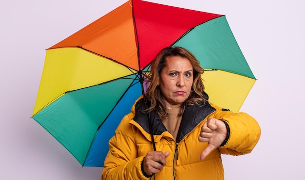 Pretty middle age woman feeling cross,showing thumbs down. umbrella concept