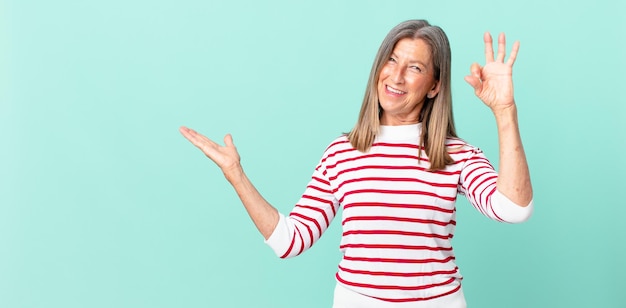 Pretty middle age woman feeling happy, showing approval with okay gesture