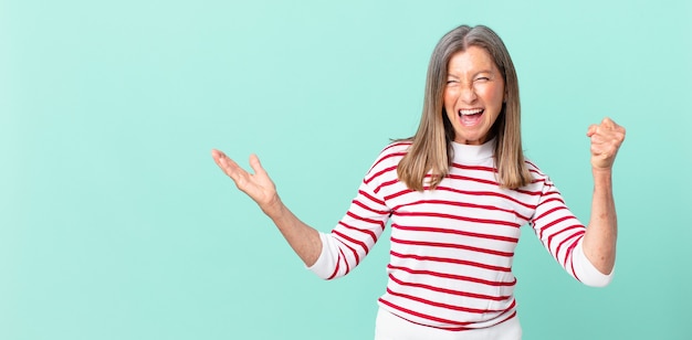 pretty middle age woman feeling shocked,laughing and celebrating success