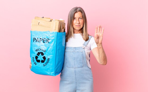 Pretty middle age woman looking serious showing open palm making stop gesture recycling cardboard concept